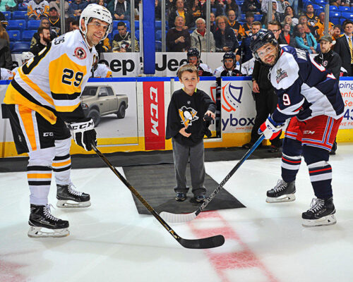 Two hockey players pose on the ice with a young boy at a Wilkes-Barre/Scranton Penguins in Wilkes-Barre, PA.