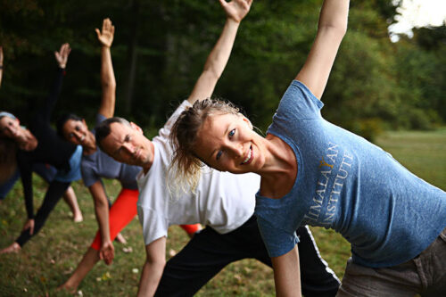 A group holds a yoga pose during an outdoor yoga session at Himalayan Institute in Honesdale, PA.