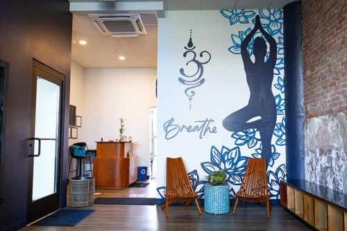 A mural featuring a figure holding a yoga pose at the entrance to Steamtown Hot Yoga & Barre in Scranton, PA.