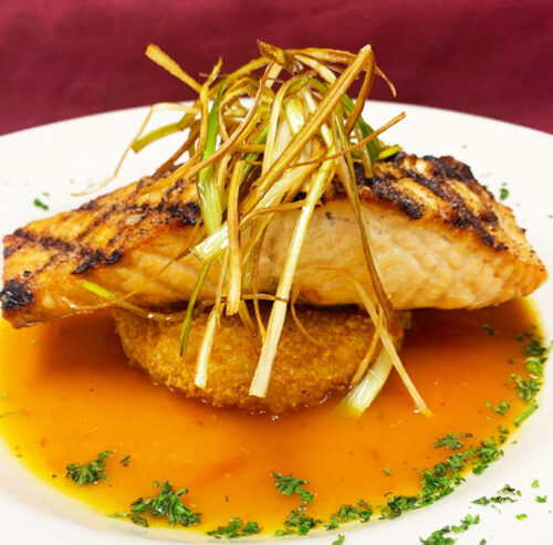 A grilled salmon fillet, topped with crispy fried leeks, served at Top of the 80's in Hazleton, PA.