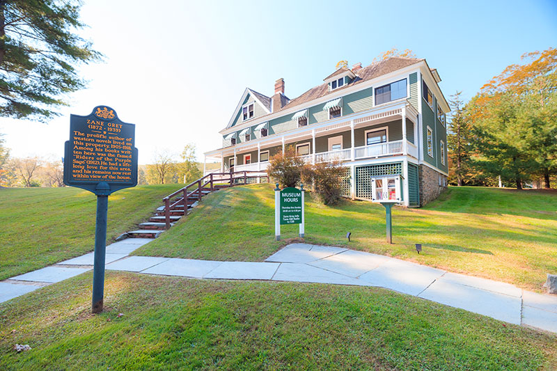 An exterior photo of the Zane Grey Museum, a two-story home located on the Lackawaxen and Delaware River in Lackawaxen, PA.