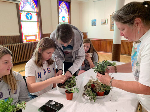 A group of girls being guided by two instructors as they pot succulents at a workshop in Tamaqua, PA.