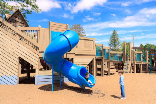 Two young boys play on a blue spiral slide on the playground at Bloomsburg Town Park in Bloomsburg, PA.