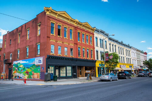 A street view of colorful buildings in Honesdale, Pennsylvania, with the Dime Bank mural prominently displayed on the left corner building.