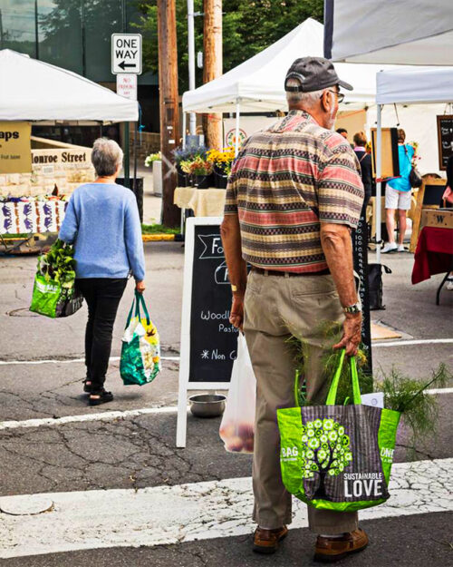 A man carries bags of fresh produce as he peruses vendor stalls at the Monroe Farmers Market in Stroudsburg, PA.