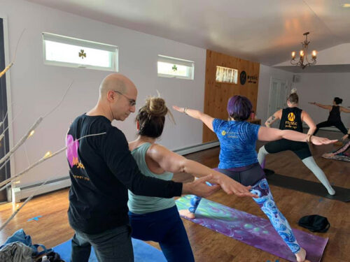 An instructor helps a student hold a pose during yoga class at Mystic power Yoga in Hazle Twp., PA.