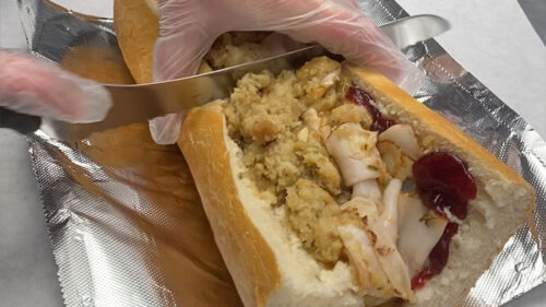 A hand cutting the big Gobbler Hoagie from Steve and Irene's Hoagies in Mayfield, PA.