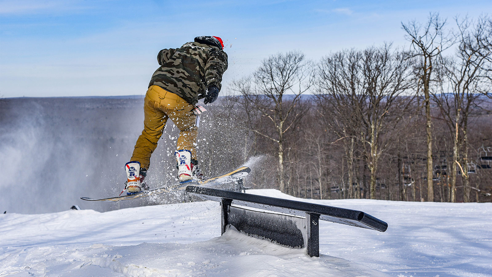A snowboarder finishes a rail slide on the terrain park overlooking the mountain at Jack Frost Ski Resort in White Haven, PA