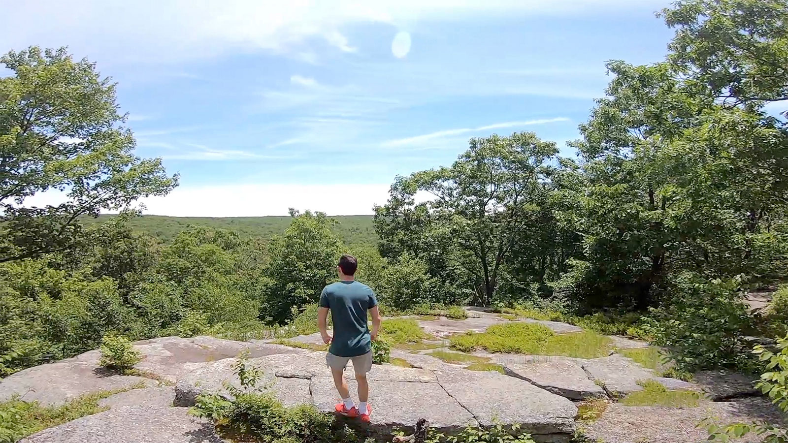 A young man stands alone admiring a sunny view across the Wyoming valley from a rock outcropping along a trail at the Bear Creek Preserve in Bear Creek, PA.