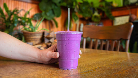 Hand holding a purple smoothie at NucleusRawFoods in Luzerne, PA.