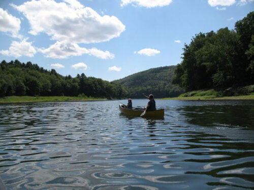 Two people are canoeing on a calm lake at Dingmans Campground in Dingmans Ferry, PA.