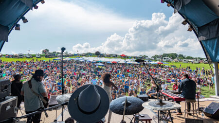 A band performing on stage in front of a packed crowd at Briggs Farm Blues Festival, an outdoor summer concert in Northeastern PA (NEPA).