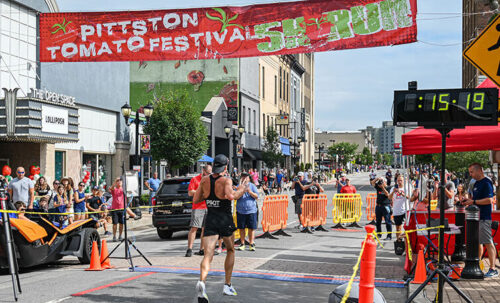 A runner crosses the finish line at the Pittston Tomato Festival 5K in Pittston, PA.