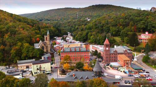 An aerial view of Jim Thorpe, Pennsylvania, nestled in a valley with St. Mark's Episcopal Church and other buildings visible among the fall foliage.