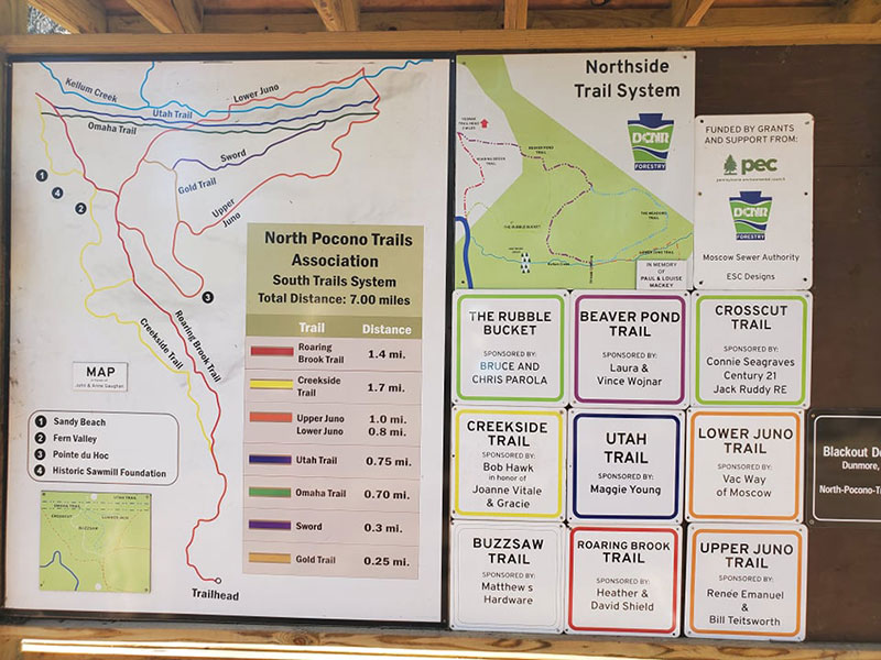 A trail map detailing trail blazes, trail names and trail distances stands at the start of the North Pocono Trail System in Moscow, PA.