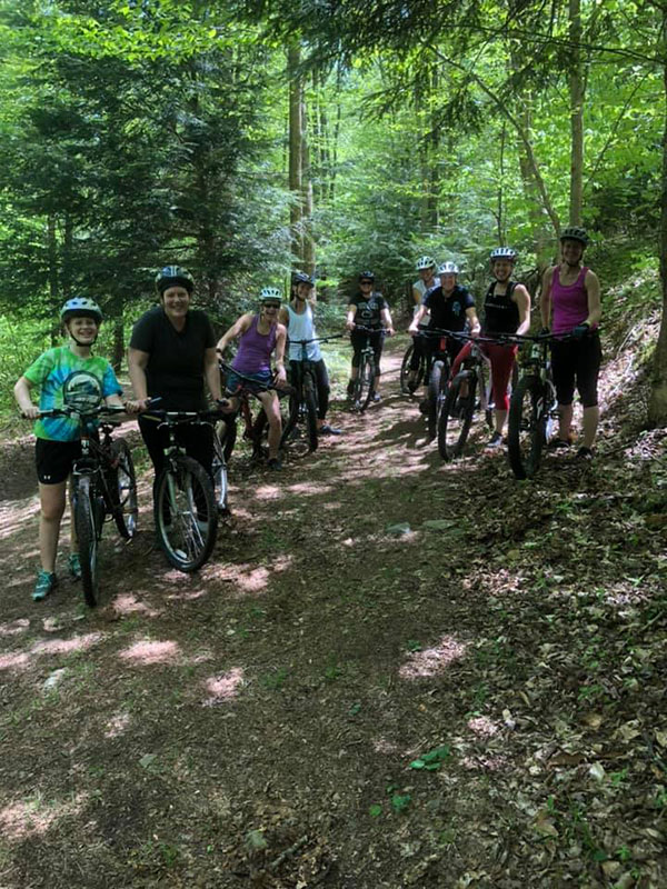 Nine cyclists from a local trail biking group pose for a photo while on a summertime ride along the North Pocono Trail System in Moscow, PA.