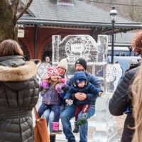 A family of four poses for a photo sitting on an ice throne sculpture at the Jim Thorpe Ice Festival in Jim Thorpe, Pennsylvania.