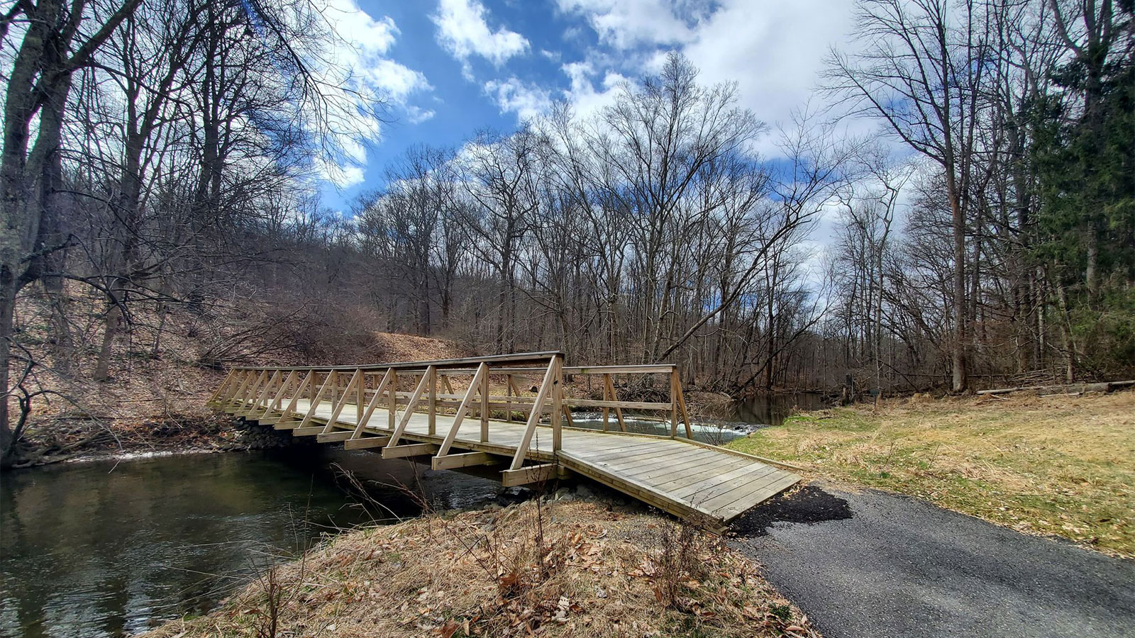 A wooden footbridge crossing a small stream on a trail at Cherry Valley National Wildlife Refuge in Stroudsburg, PA.