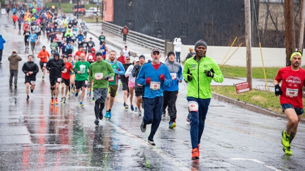 Runners participate in the Scranton Half Marathon, racing along city streets on a rainy day.