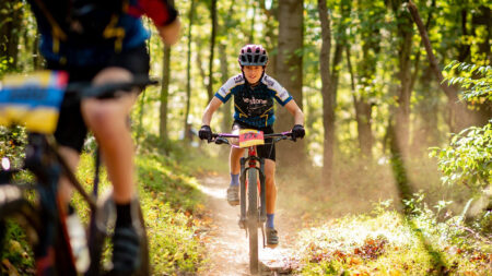 A teen rider from the nonprofit Keystone Mountain Bike Team navigates a forest trail on his mountain bike.