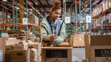 A volunteer packs a box with canned goods inside the CEO/Weinberg Northeast Regional Food Bank warehouse in Pittston, PA.