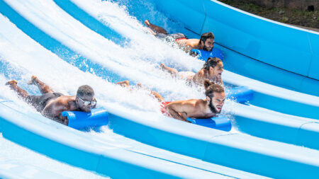 Four adults riding down a water slide on blue mats at Montage Mountain Waterpark in Scranton, PA.