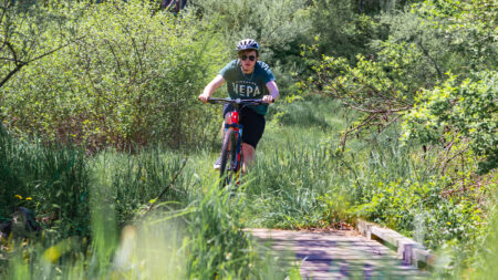 A young man prepares to cross a wooden bridge while mountain biking at the Ziegler Preserve in Dalton, PA.