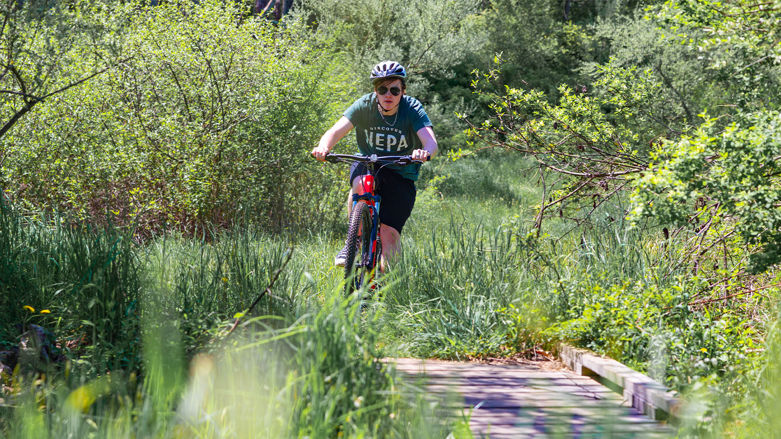 A young man prepares to cross a wooden bridge while mountain biking at the Ziegler Preserve in Dalton, PA.