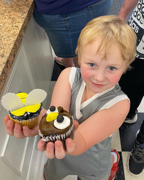 A child holding up two decorated cupcakes at Main Street Makery in Stroudsburg, PA.