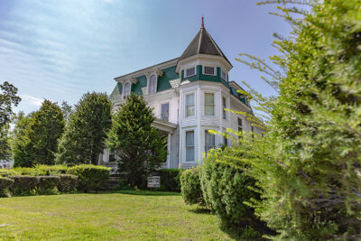 A white mansion with a prominent turret along the Historic tunkhannock Walking Tour in Tunkhannock, PA.