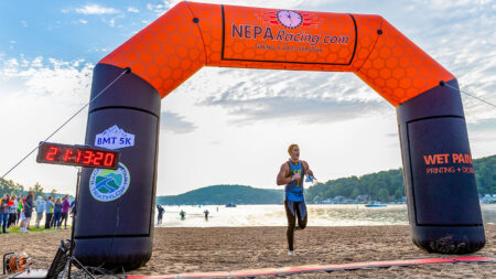 A swimmer exits the lake under a NEPARacing.com inflatable arch during the Back Mountain Triathlon in Harveys Lake, PA.