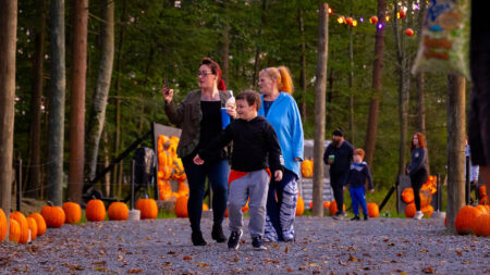 Families walking the Glowing Pumpkin Trail at Roba Family Farms in North Abington Township, PA, a top Halloween Event for Kids in NEPA, surrounded by carved pumpkins and festive lights during the evening.