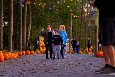 Two women and a young boy check out the Glowing Pumpkin Trail at Roba Family Farms in North Abington Twp., PA.