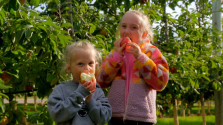 Two girls biting into an apples at Lakeland Orchard & Cidery in Scott Twp., PA.