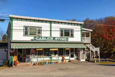 A daytime exterior shot of Cable's General Store, a two-story white building with green trim and a striped green and white awning, located in Union Dale, Pennsylvania.