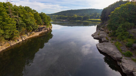 The Delaware River gently flows through bedrock cliffs within the Pocono Mountains.