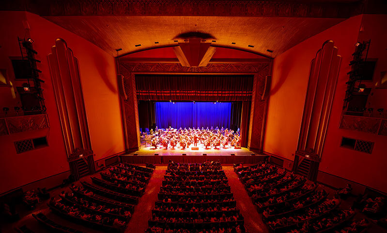 A balcony view of an orchestra performing on the Kirby Center stage. 