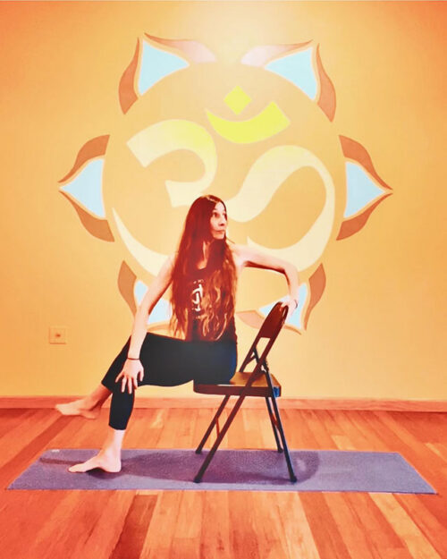 A woman holds a pose during a chair yoga session at Yoga House Stroudsburg in Stroudsburg, PA.