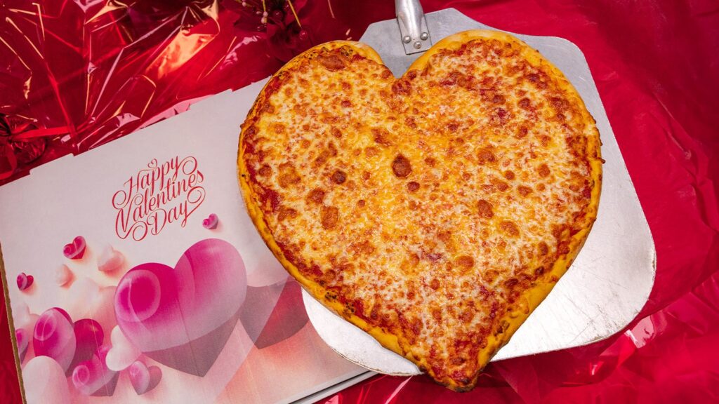 A heart-shaped cheese pizza on a red background at Alfredo's Cafe in Scranton, PA.