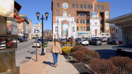 A street view in Pittston, Pennsylvania, shows a woman walking on the sidewalk past a 