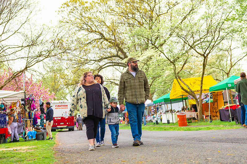 A family walks among various vendor tents at the annual Cherry Blossom Festival held at Kirby Park in Wilkes-Barre, PA.