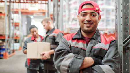 Three workers in a distribution facility pose for a photo.