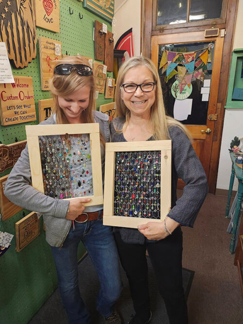 Two women smiling and showing this framed beaded art projects from The Crooked Branch in West Pittston, PA.