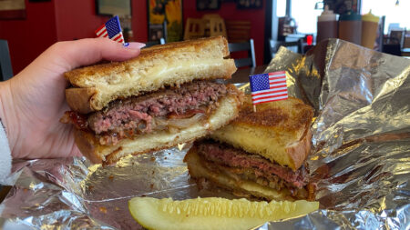 A hand holding the Not So Patty Melt Burger from American Grill in Exeter, PA.