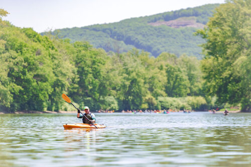 A lone kayaker paddles ahead of a larger group of kayakers on the Susquehanna RIver.