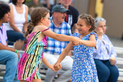 Two young girls dance in front of a seated crowd at Hazleton's Rockin ' The Mountain free summer concert series.