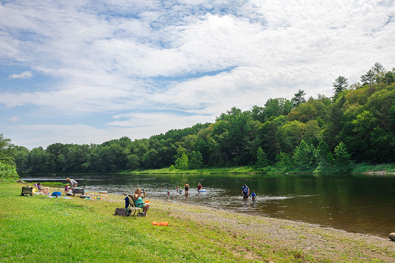 Families gather along the shore to take a dip in the Delaware River at Milford Beach in Milford, PA.