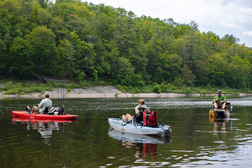 Three people are kayaking and fishing on the Delaware River at Milford Beach in Milford, PA.