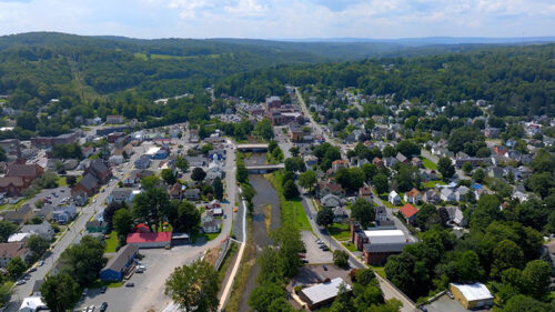 An aerial view of Honesdale, Pennsylvania, from Irving Cliff featuring a river running through the town and surrounding green hills.