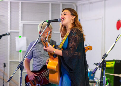 A female musician plays the guitar while singing during the Pittston Tomato Festival in Pittston, PA.
